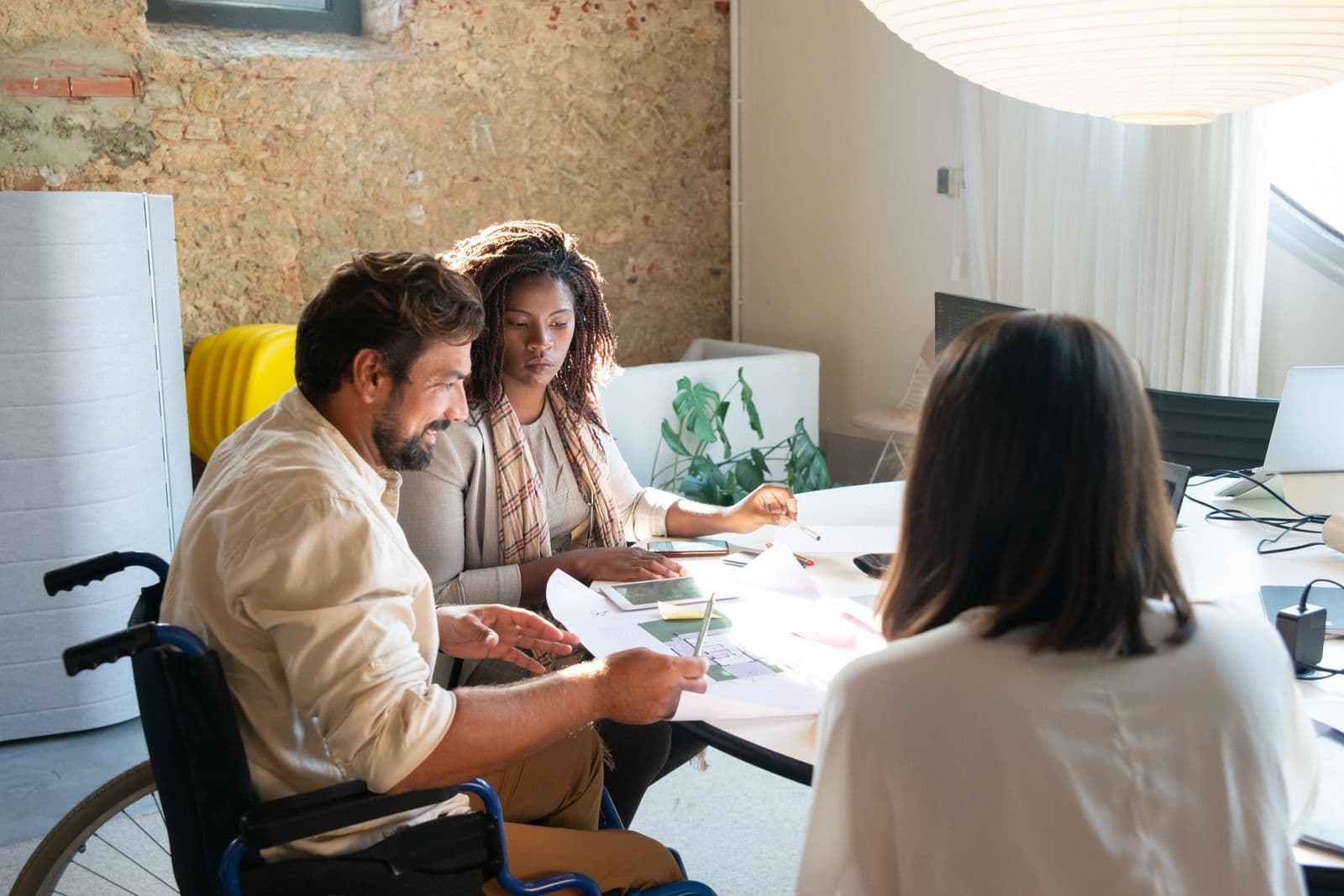 A wheelchair user reviewing plans with colleagues around a table