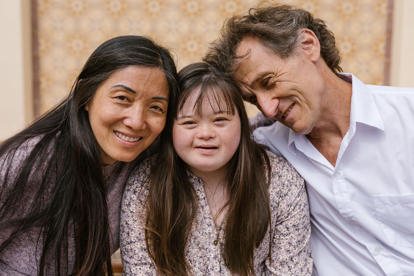 Parents and their daughter, who has Down syndrome, smiling closely together